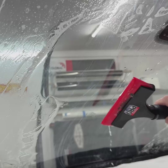 Demonstration of the Sledgehammer 93 durometer yellow squeegee blade in action, extracting solution during windshield tinting for a smooth, flawless finish.