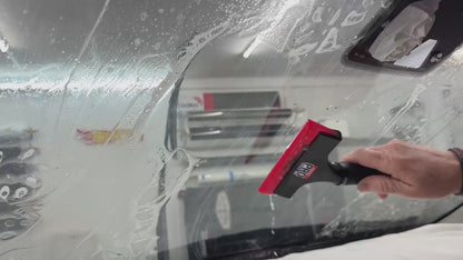 Demonstration of the Sledgehammer 93 durometer yellow squeegee blade in action, extracting solution during windshield tinting for a smooth, flawless finish.