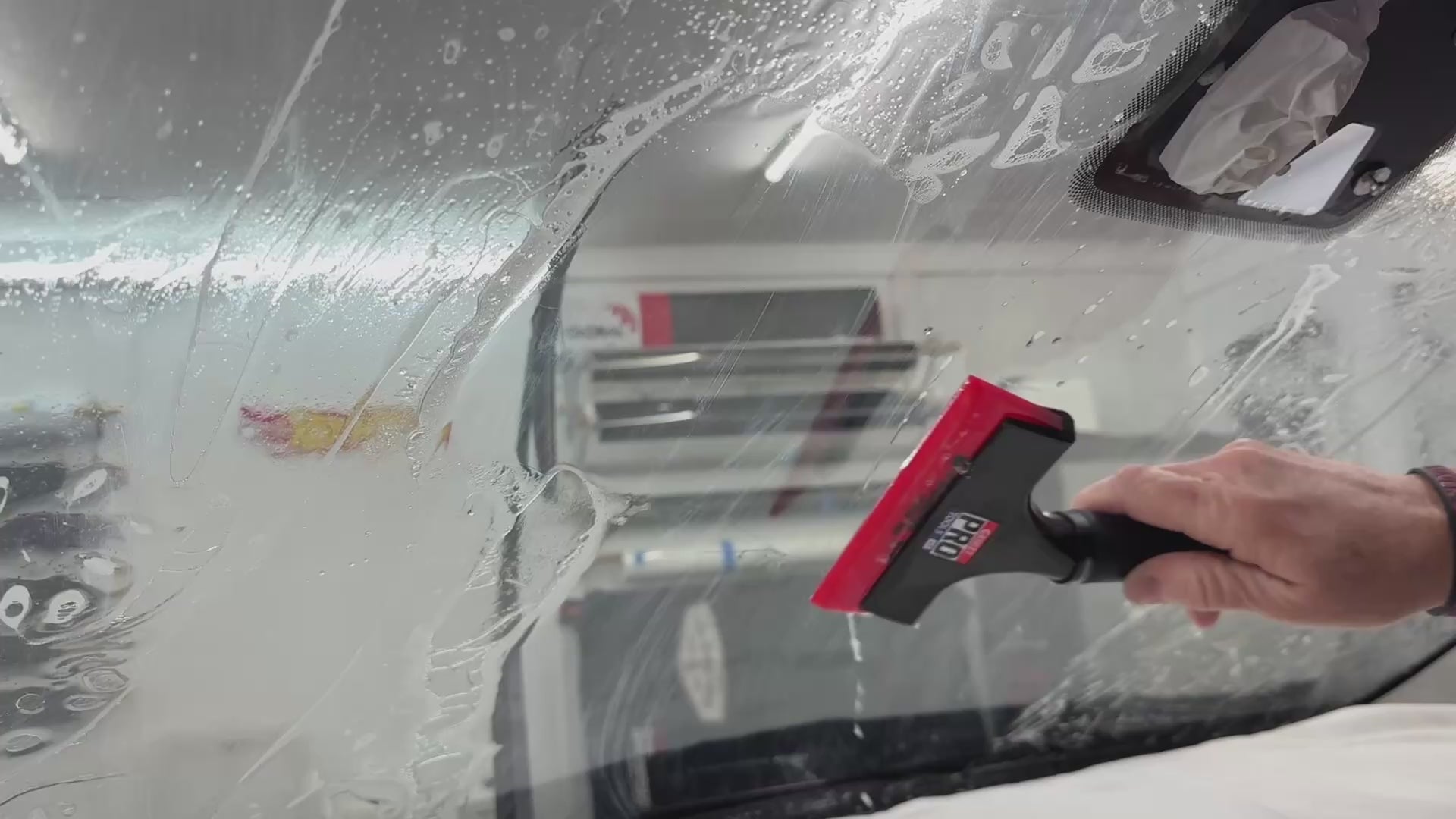 Demonstration of the Sledgehammer 93 durometer yellow squeegee blade in action, extracting solution during windshield tinting for a smooth, flawless finish.